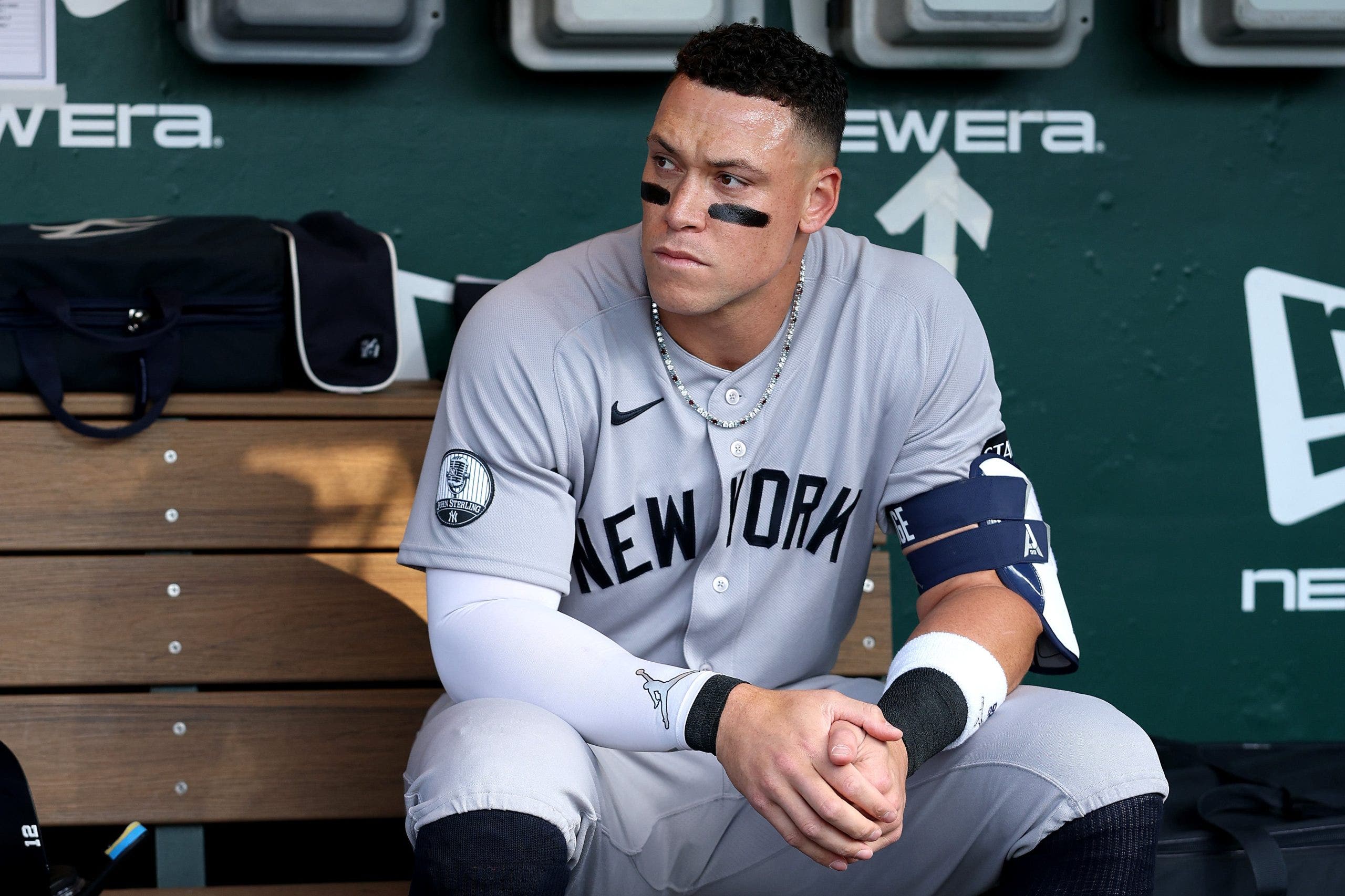 New York Yankees captain Aaron Judge standing in the dugout in uniform while sidelined by a rib stress fracture