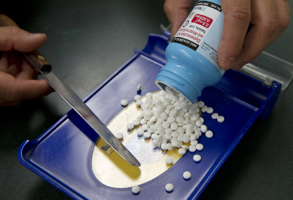 A pharmacist counts prescription tablets at a pharmacy counter. Source: The Colorado Sun