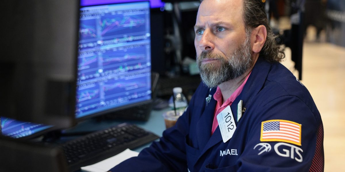 Traders on a stock exchange floor watching screens as the Dow Jones Industrial Average posts a record close of 52,900.07