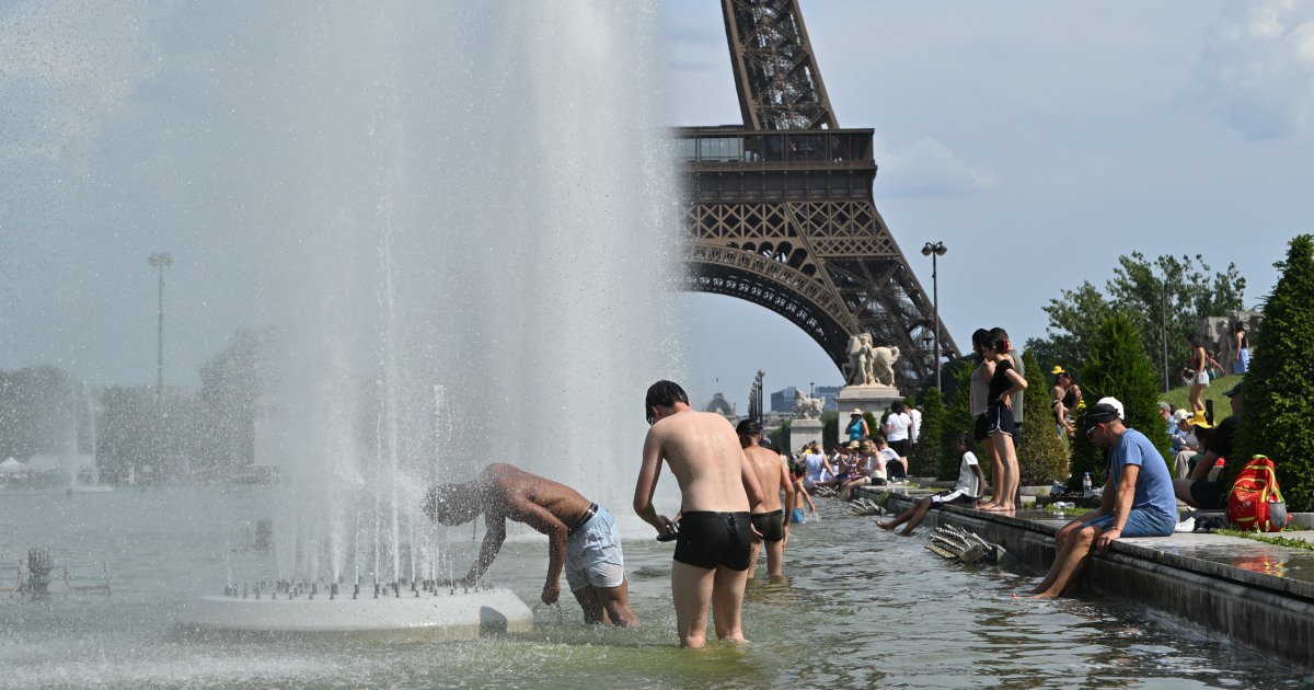 A pedestrian shields from the sun during Europe's record late June 2026 heatwave as a public thermometer displays extreme temperatures