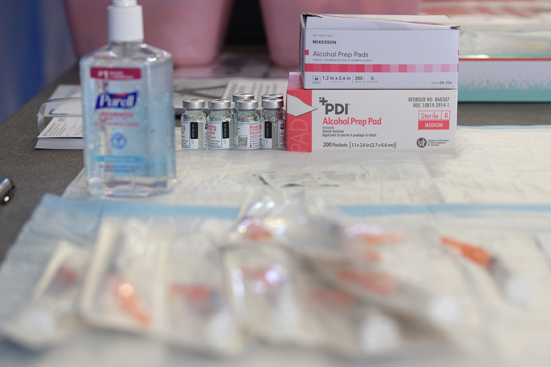 Syringes and vials of Moderna covid vaccine laid out on sanitized paper ahead of administration at a military vaccination site. Photo: Airman 1st Class Rebeckah Medeiros, U.S. Air Force / Wikimedia Commons, Public domain