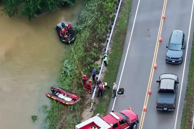 Emergency workers wade through floodwater in Lesterville, Missouri, after the Black River overran its banks. Photo: KTVI via AP
