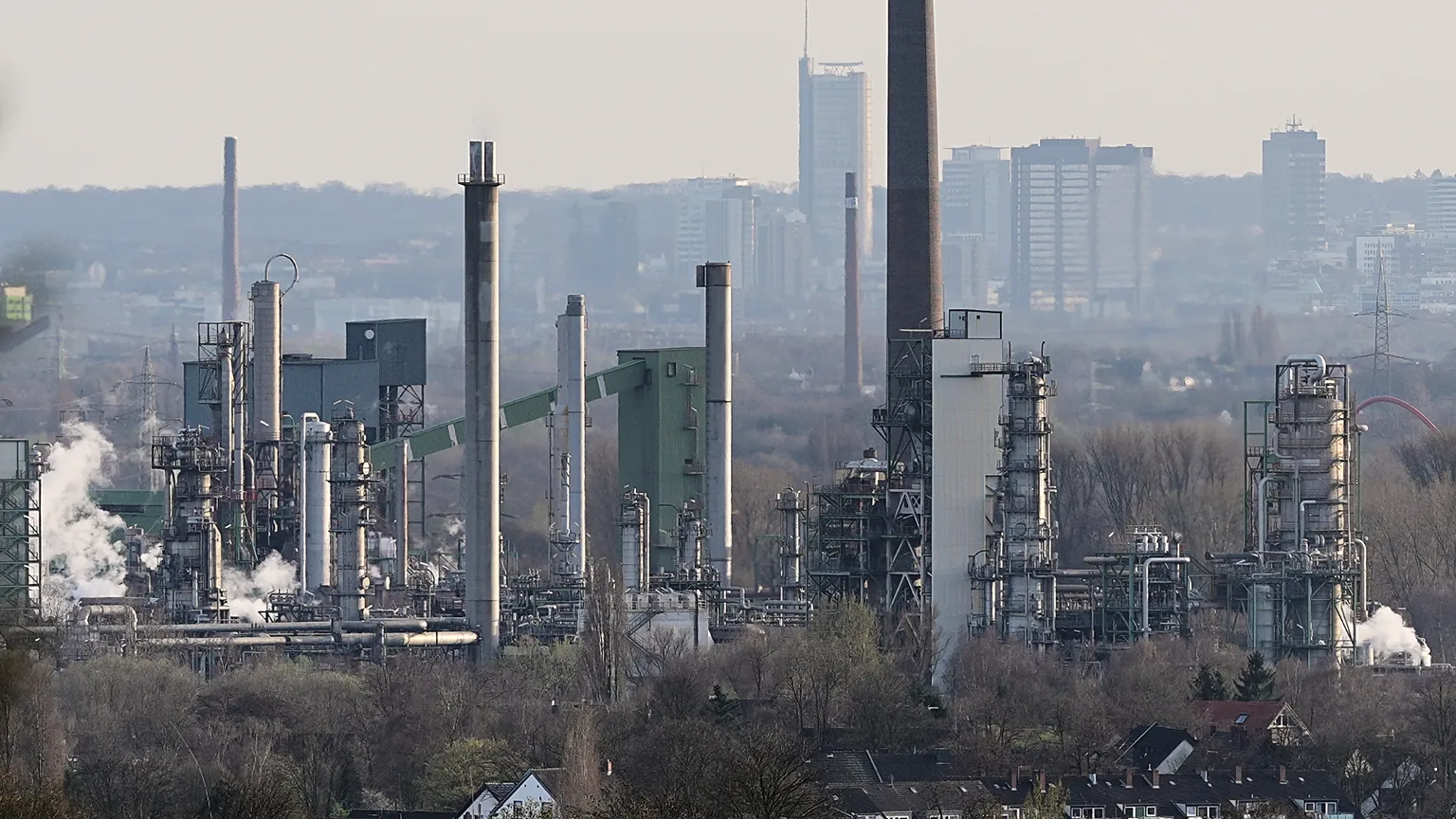 Oil and gas infrastructure at a Gulf export terminal against a hazy sky, illustrating the energy shock behind the OECD downgrade. Photo: Euronews