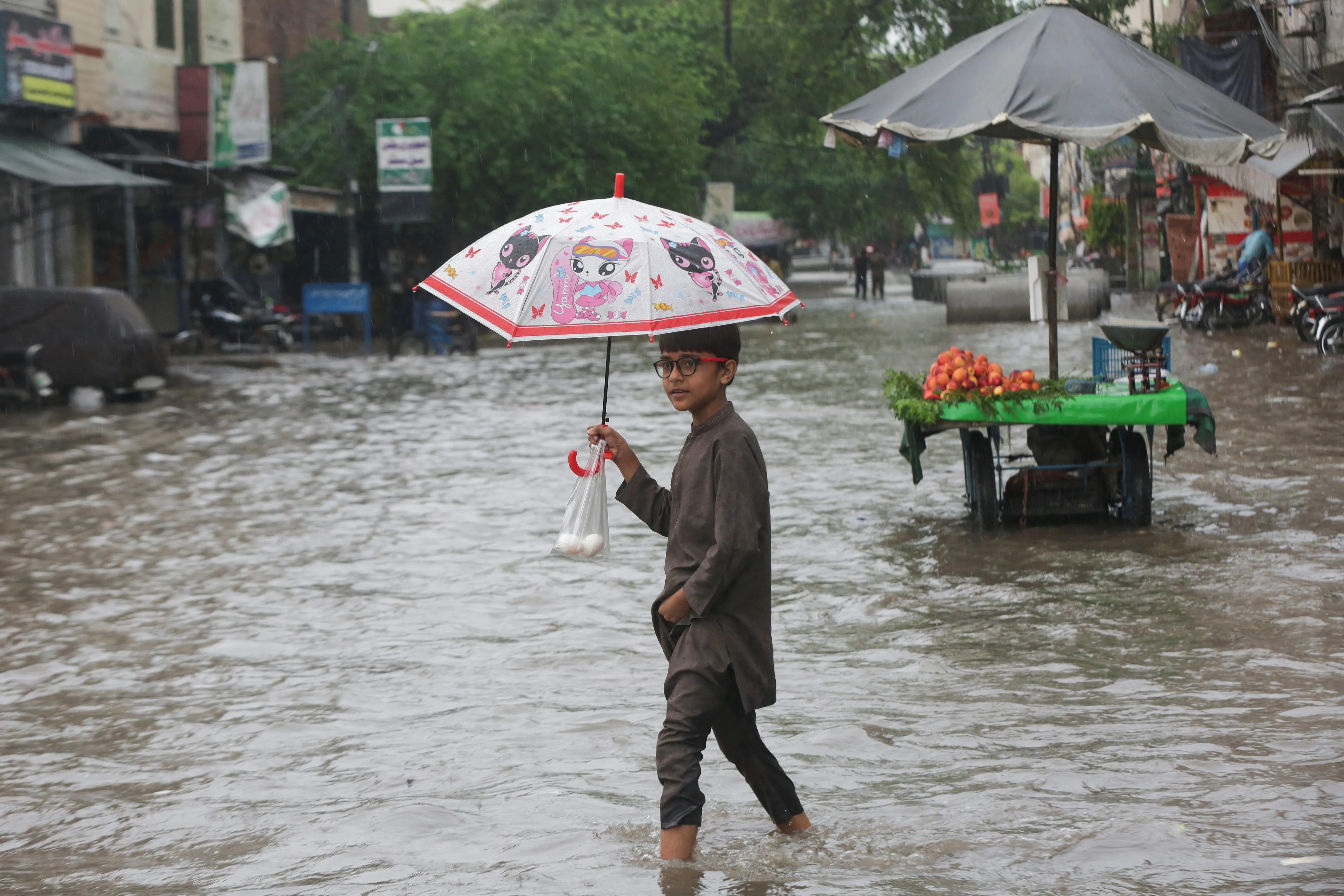 A child holding an umbrella wades through a flooded street in Lahore after monsoon rain in Pakistan. Photo: Al Jazeera