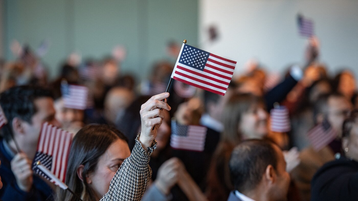 People wave U.S. flags during a naturalization ceremony in Boston. Photo: NPR